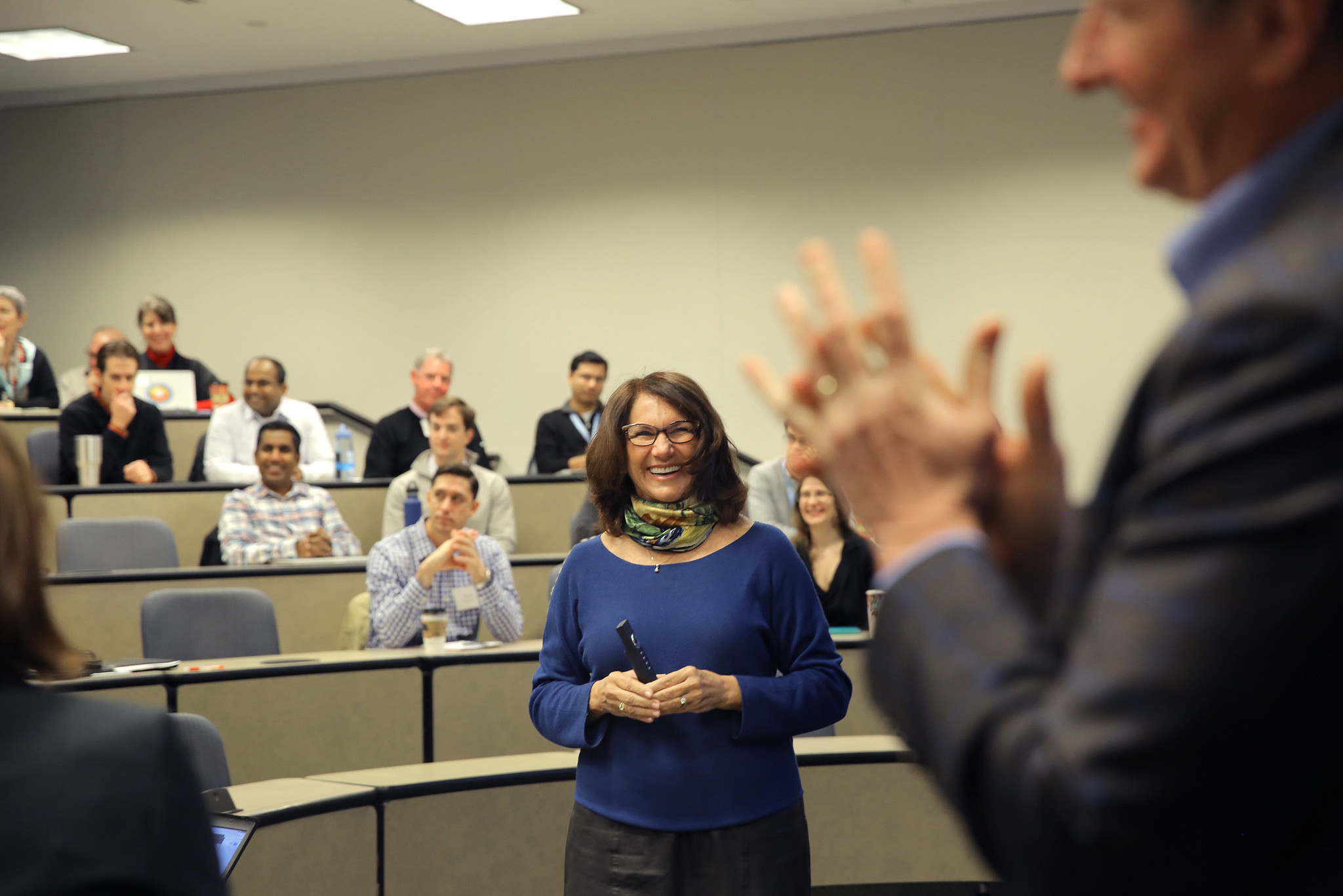 Woman laughing at a man gesturing, full classroom behind her