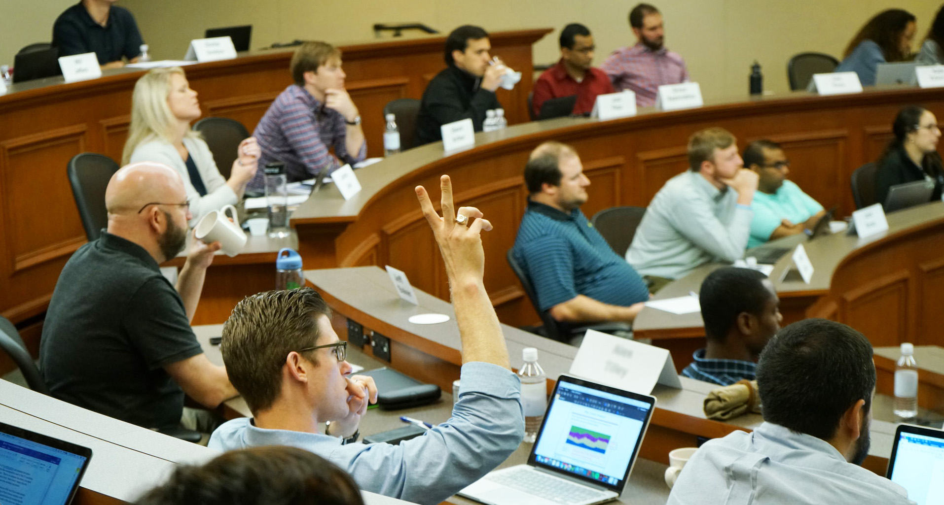 Man raising hand in a classroom full of students