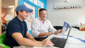 MBA student Alex Brandwein and Scott Maitland holding papers at a table at Launch Chapel Hill