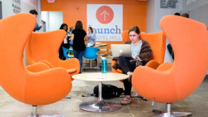 In launch co-working space student sits in orange chair typing on computer