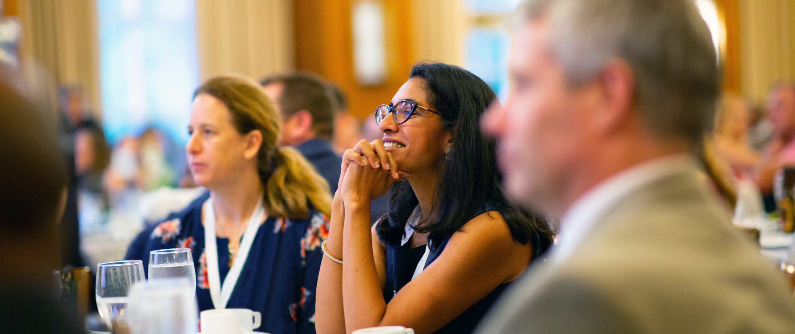 Businesspeople in a meeting in a University of North Carolina at Chapel Hill classroom smiling while listening to a presenter.