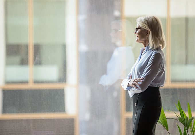 Businesswoman looking out a window while thinking.