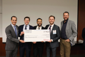 Four men hold the first place check for $15,000 address to Chicago Both Business School.