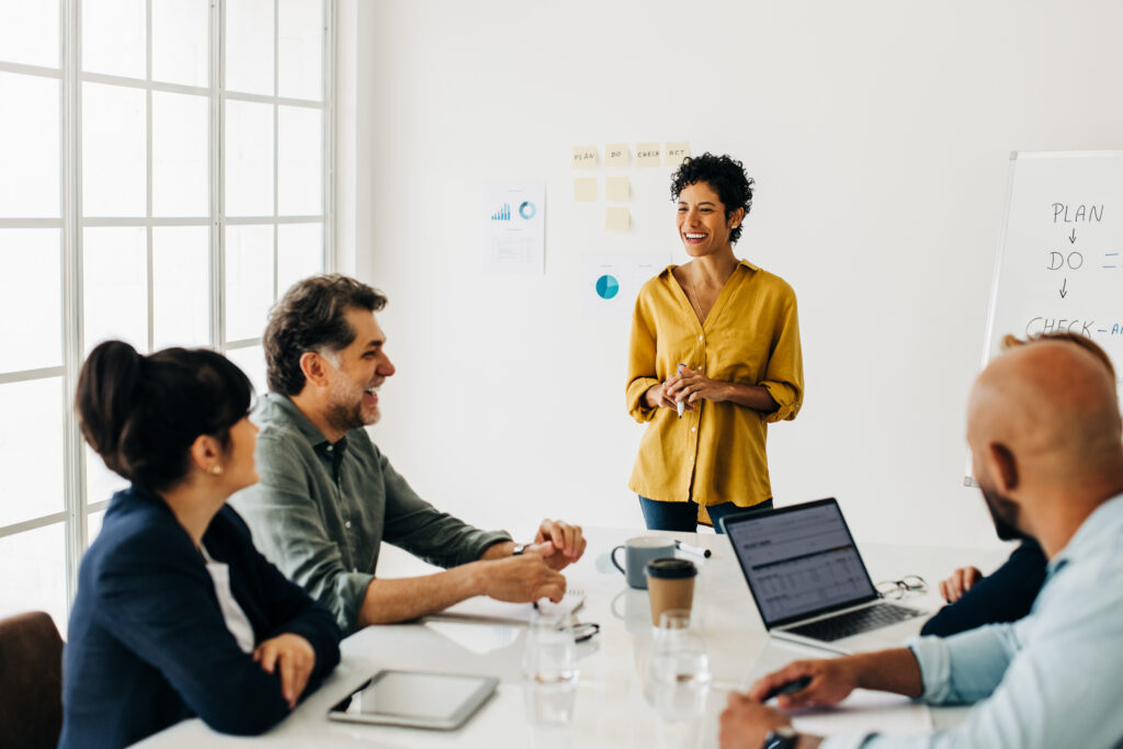 Smiling businesswoman presenter overseeing a discussion during a team meeting.