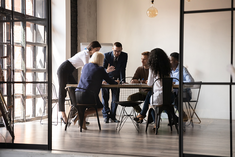 Businesspeople in a modern boardroom sitting around a table and engaging in a discussion as they analyze documents.