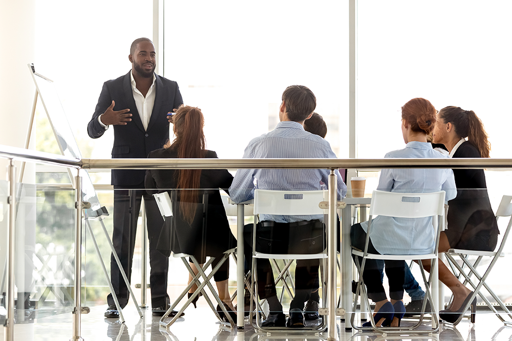 Businessman presenting to a group of coworkers in a modern conference room.