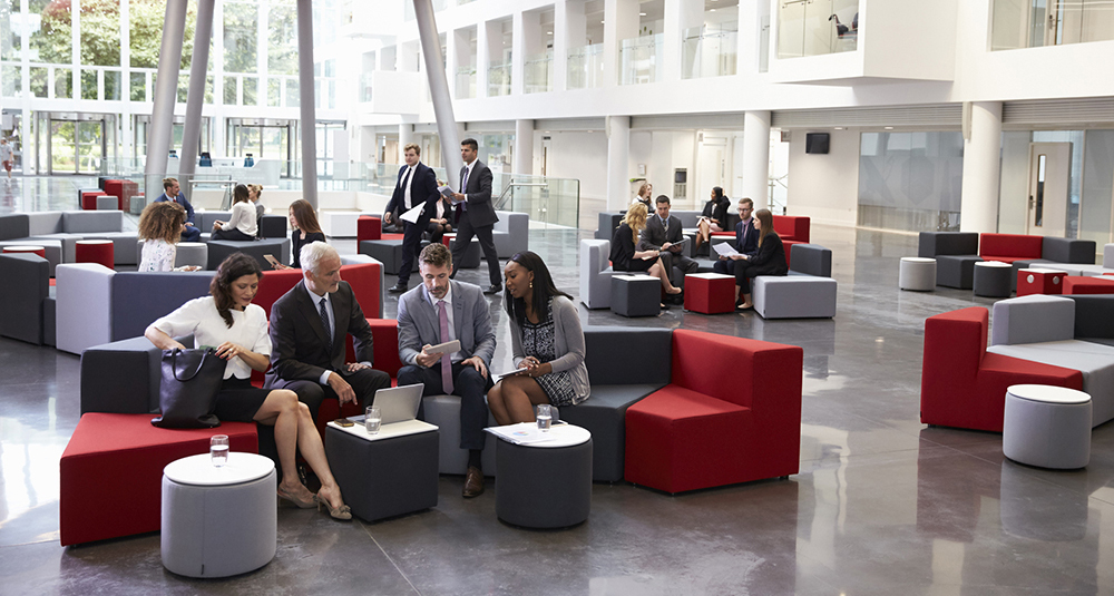 Businesspeople Meeting In Busy Lobby Of Modern Office