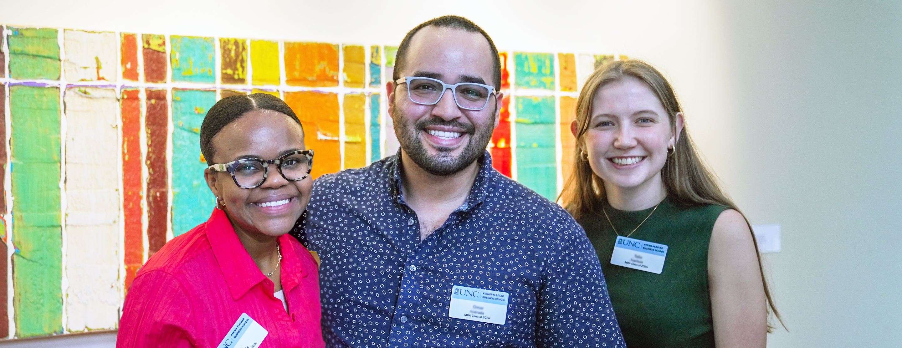 Three students stand smiling looking at the camera.