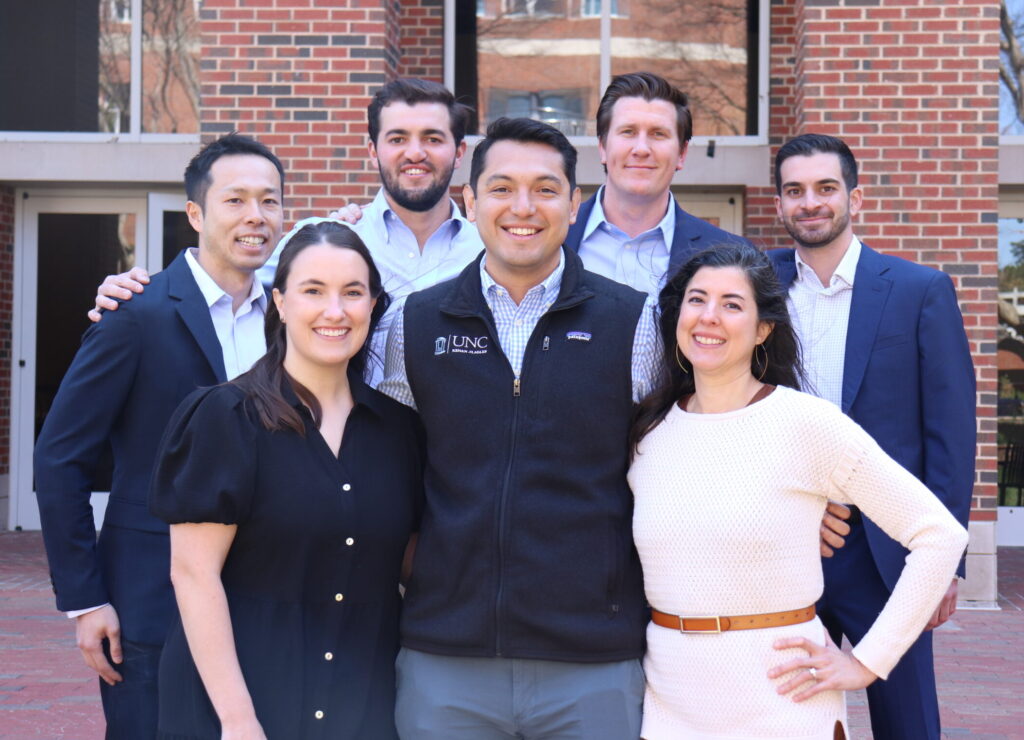 Seven members of the UNC MBA Real Estate Club Board stand together posed for a photo.
