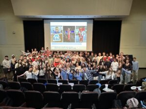 Students and community members pose for a large group photo inside of Koury Auditorium.