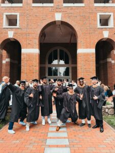 Class of 2025 MBA students strike a pose in front of McColl Building.