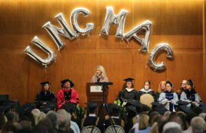 Commencement speaker Hillary Salo (BSBA ’02, MAC ’03) speaks under balloons that spell out “UNC MAC.”