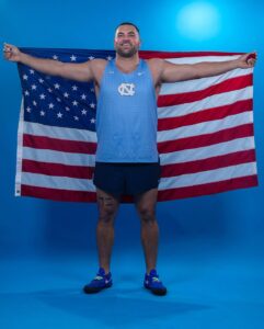 Tommy Kitchell (MAC ’25) holds up an American flag behind him.