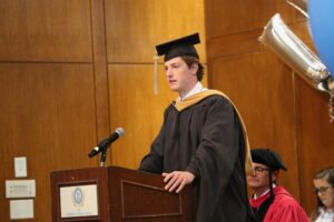 Luke Gentry (BSBA ’24, MAC ’25) speaks at the podium.