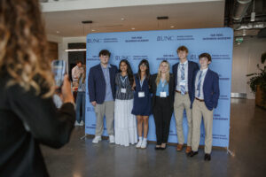 Attendees get their photo taken in front of a UNC Kenan-Flagler Tar Heel Business Academy step and repeat.