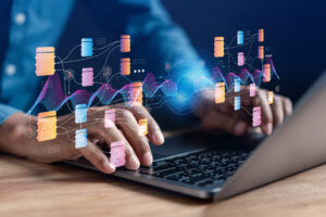 Hands typing on a laptop with icons representing AI and data analytics floating above.