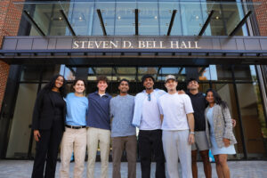 A group of students in front of the main entrance to Steven D. Bell Hall.