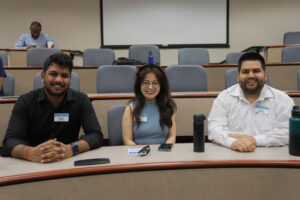 Three smiling MBA students (2 male and 1 female) in classroom