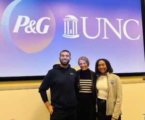 Sophia Jenkins (BSBA ’22), Adrianna Hernandez Cepero (BSBA ’23) and Jeremy Baslious (BSBA ’20) pose together in front of screen that has P&G and UNC-Chapel Hill’s logos on it.