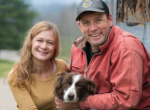 Couple sitting with dog smiling at camera