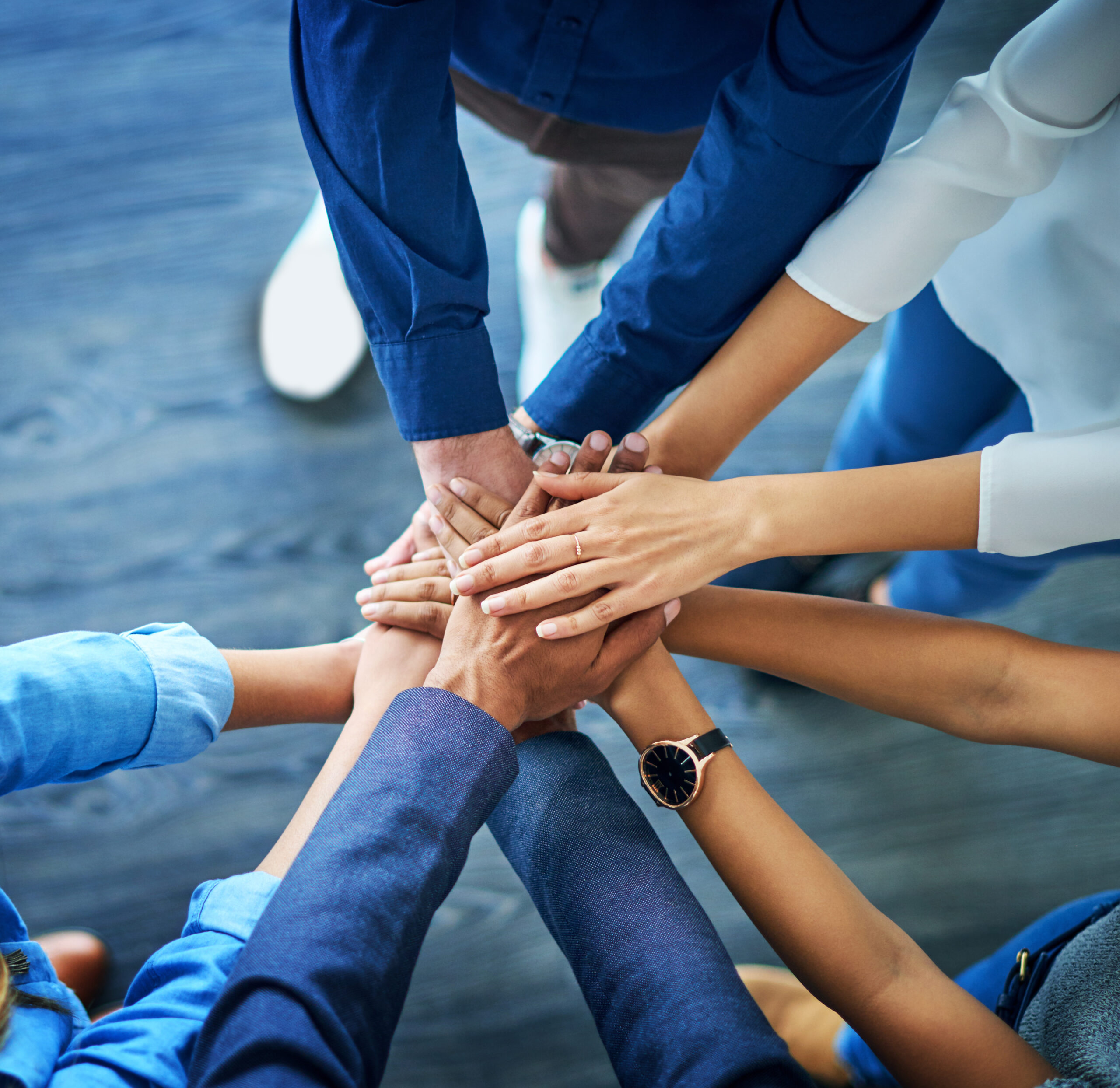 High angle shot of a group unrecognizable businesspeople joining their hands together in unity.