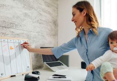 Mother working from home holding her child