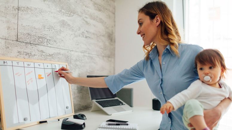Mother working from home holding her child