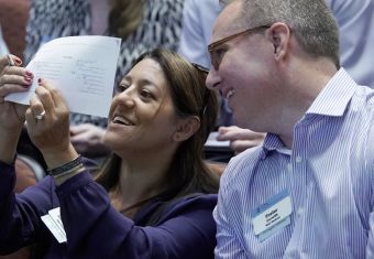 Woman and man laughing as they look at a piece of paper she's holding