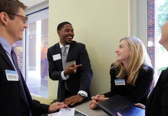 Two women and two men laughing in in a hallway