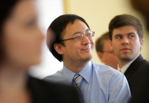 Man smiling, flanked by others, all in business professional