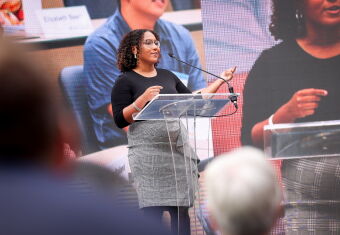 A woman stands at a podium giving a presentation