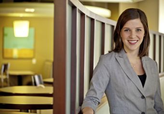 Woman in a blazer smiling in front of seating area