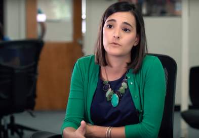 Allison Elia sitting in an office chair, talking and gesturing