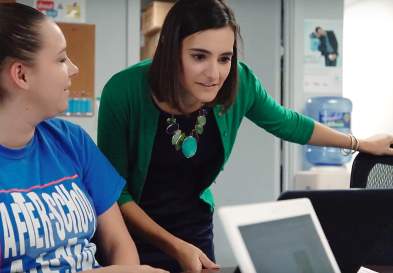 Allison Elia looking at a laptop, being looked at by the woman next to her