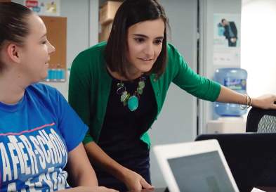 Allison Elia looking at a laptop, being looked at by the woman next to her