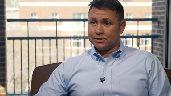 Brad Bertinot talking on a patio, with buildings in the background