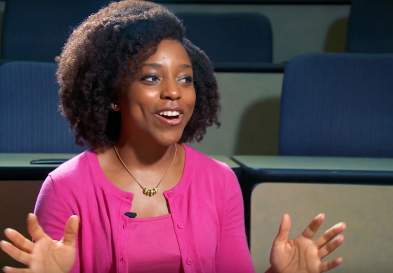 Dominique Stephenson in a classroom, smiling as she talks and gestures, glances to the left