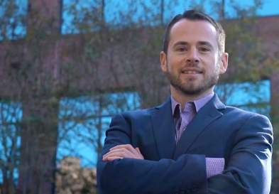 Jason Pomerantz standing with crossed arms in front of a building