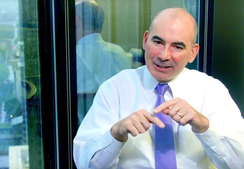 Trent Gazzaway explaining and gesturing, sitting in front of a window