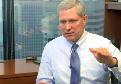 Jeff Burgess gesturing and talking, in a highrise office