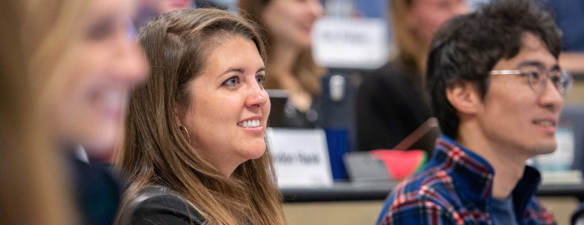 A woman sits in class smiling