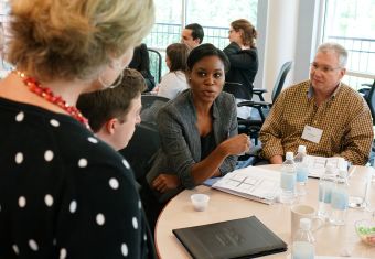 Group sitting around a circular table, with one woman talking while the others listen