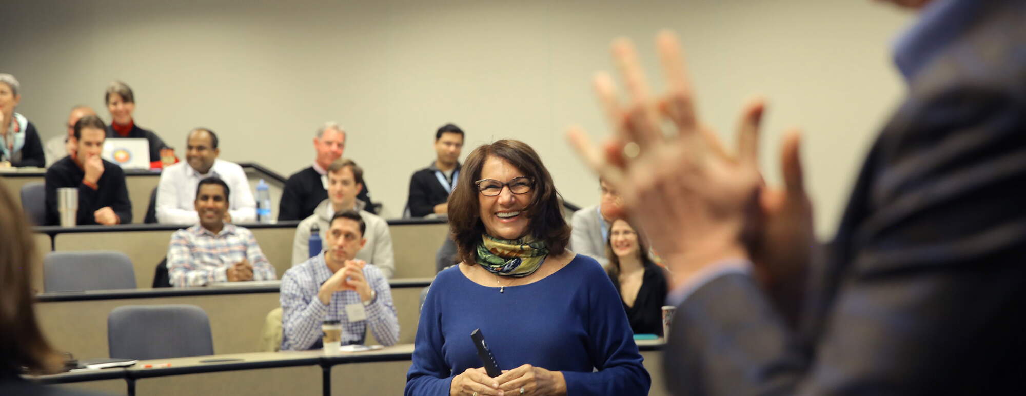 Woman laughing at a man gesturing, full classroom behind her