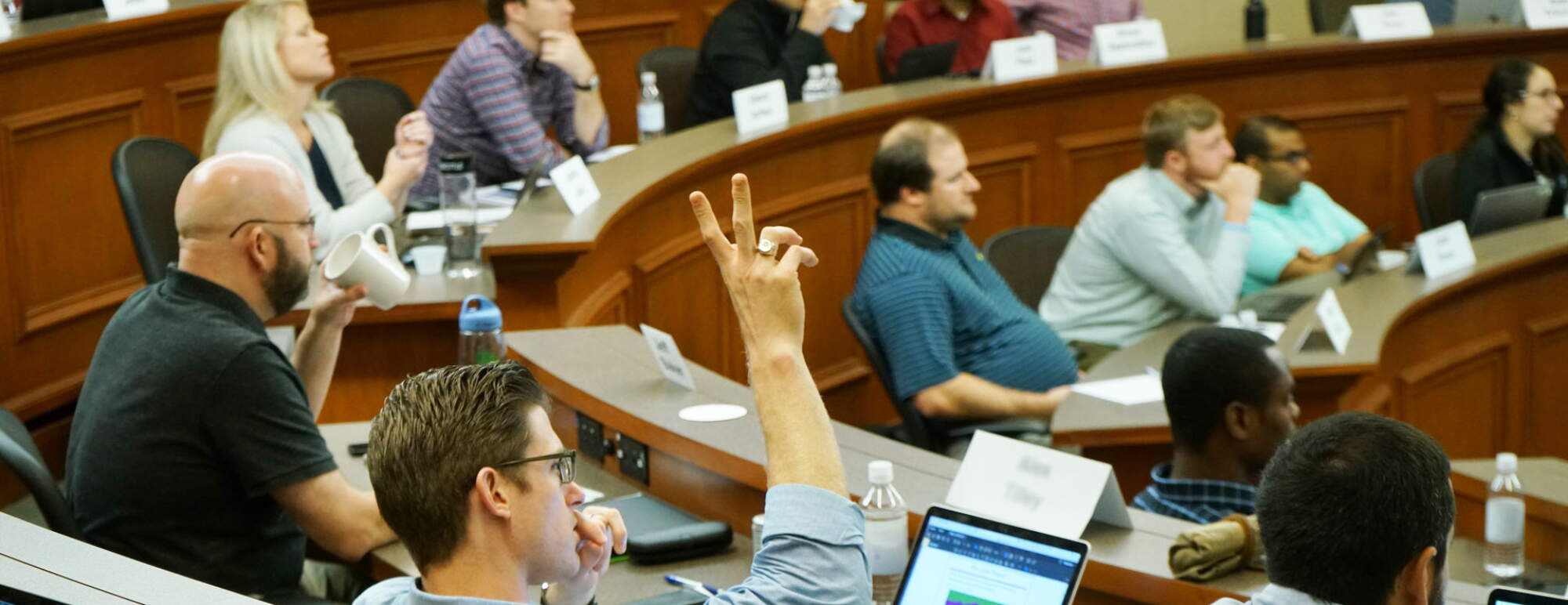 Man raising hand in a classroom full of students