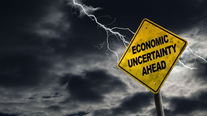 Stormy weather with a sign that reads economic uncertainty ahead.