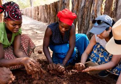 South Africa students apply new clay to a home in Zimbabwe village