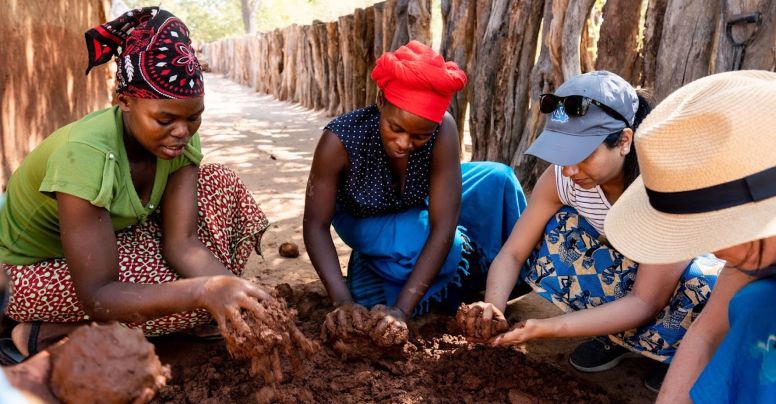 South Africa students apply new clay to a home in Zimbabwe village