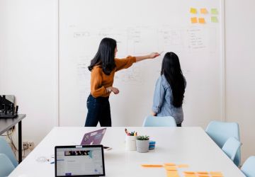 Student and Teacher Talking In Front Of Whiteboard In An Office