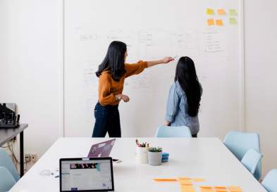 Student and Teacher Talking In Front Of Whiteboard In An Office