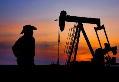 cowboy standing in front of oil pumpjack